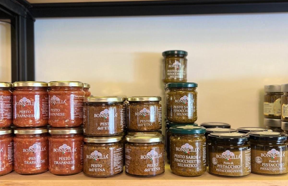 Vasetti Bonsicilia di pesto trapanese, dell'Etna, sarde e finocchietto selvatico e pistacchio impilati su mensola in legno
